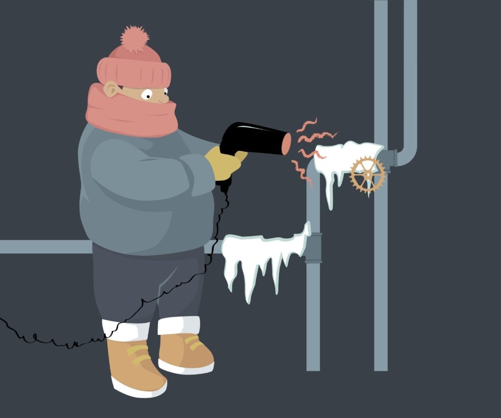 A person attempting to unfreeze frozen water pipes with a hair dryer